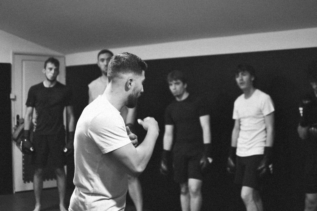 Entraîneur expliquant la garde de boxe à un groupe de débutants chez IMPACT