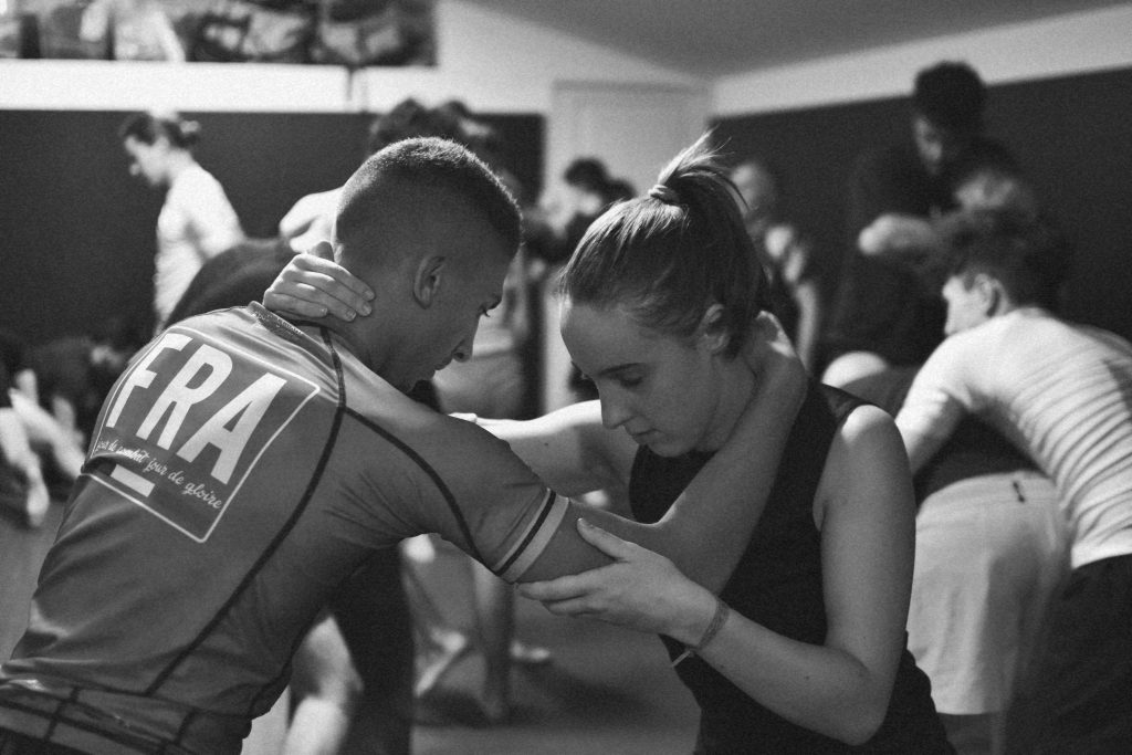 Femme pratiquant le Grappling avec un partenaire pendant un entraînement mixte