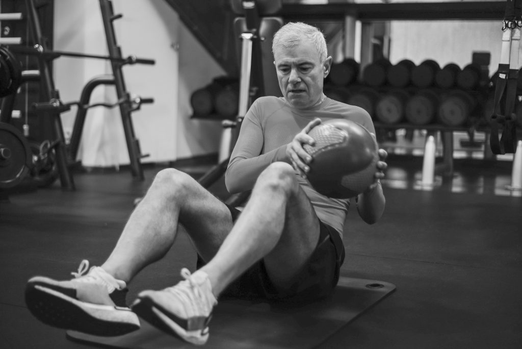 Homme senior réalisant un exercice de renforcement avec un medicine-ball