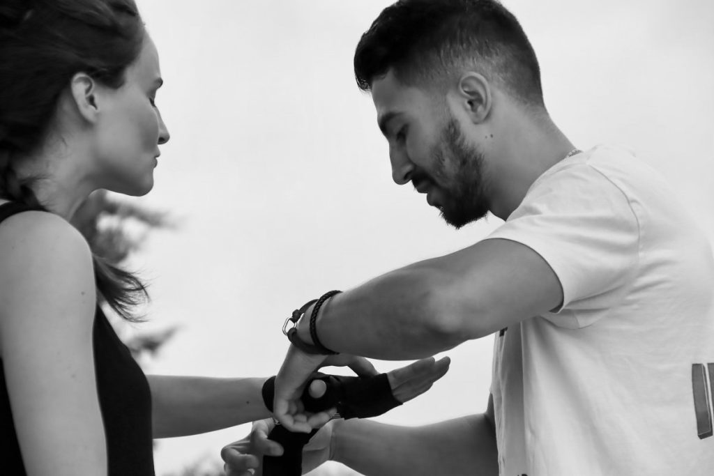 Coach sportif aidant une pratiquante à mettre ses bandes de boxe à Aix-en-Provence
