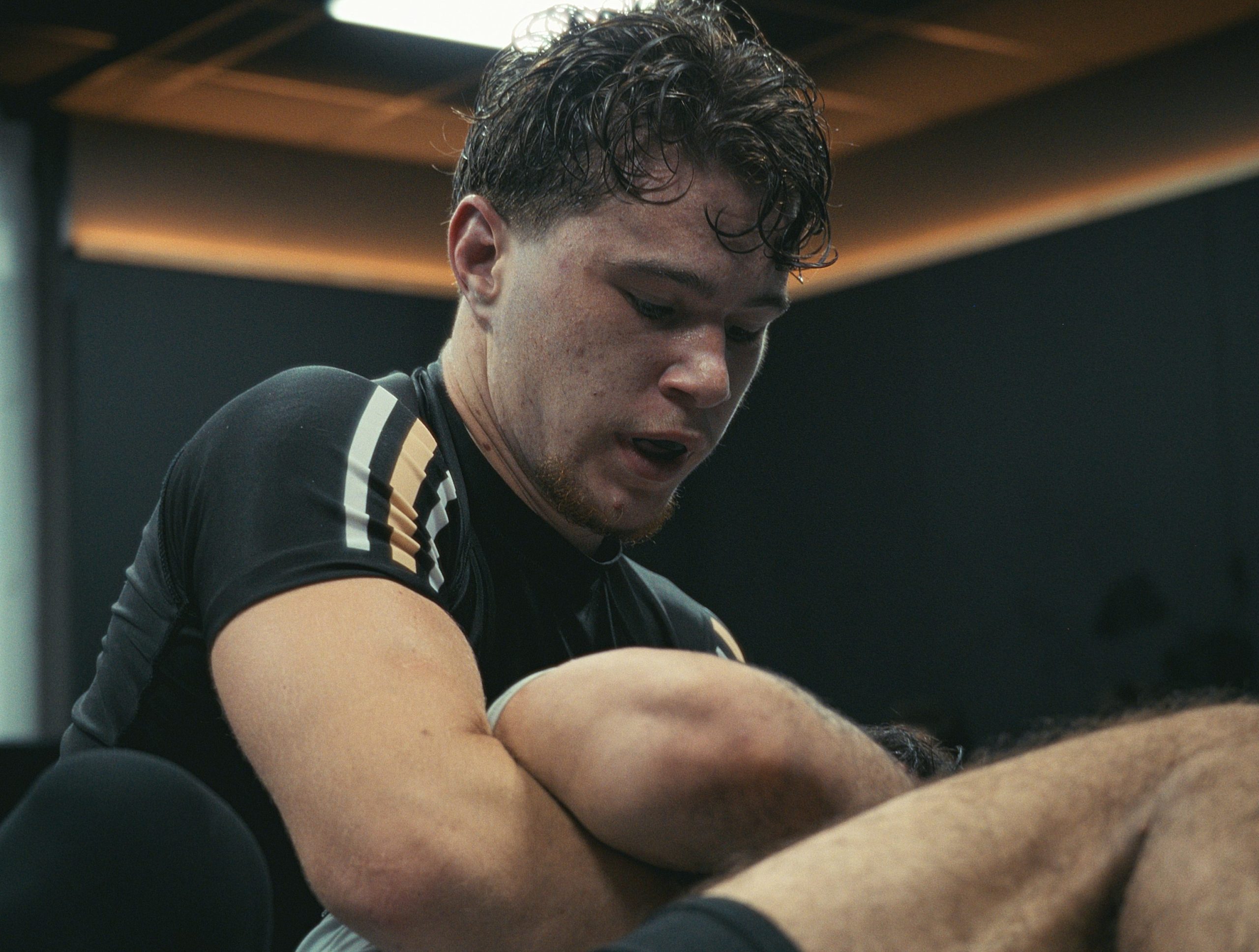 Pratiquant de Jiu-jitsu Brésilien engagé dans un effort intense pendant un combat au club IMPACT à Aix-en-Provence.