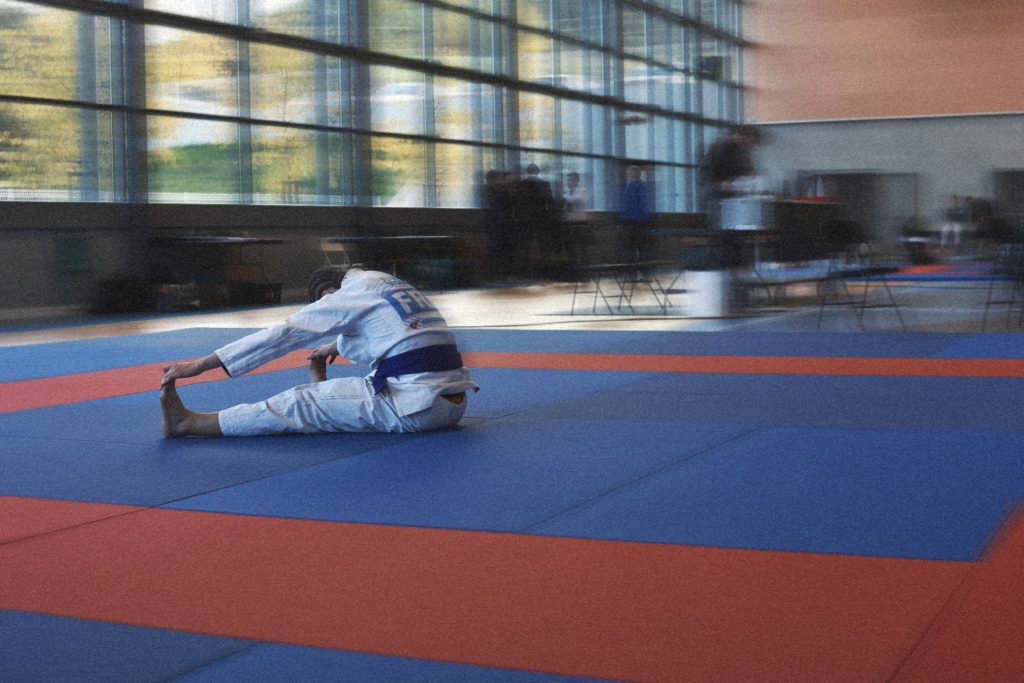 Pratiquant de Jiu-jitsu Brésilien en kimono récupérant seul sur le tatami après l’effort.