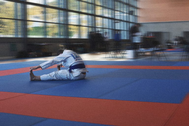 Pratiquant de Jiu-jitsu Brésilien en kimono récupérant seul sur le tatami après l’effort.