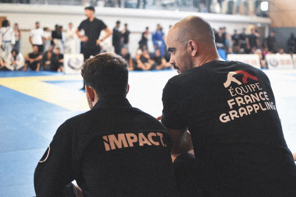 Entraîneur de Jiu-jitsu Brésilien échangeant avec un compétiteur IMPACT pour organiser sa charge d’entraînement et sa récupération.