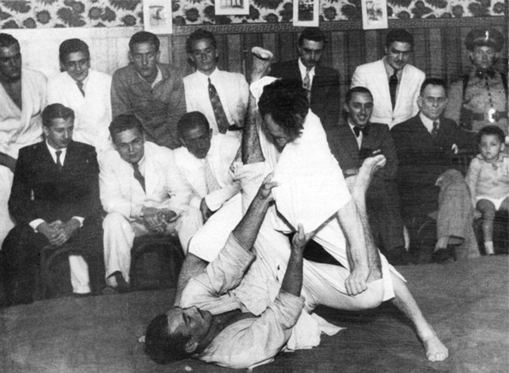 Photographie historique de Carlos et Hélio Gracie en démonstration de jiu-jitsu brésilien vers 1934, montrant une tentative de passage de garde lors d'un combat au sol.