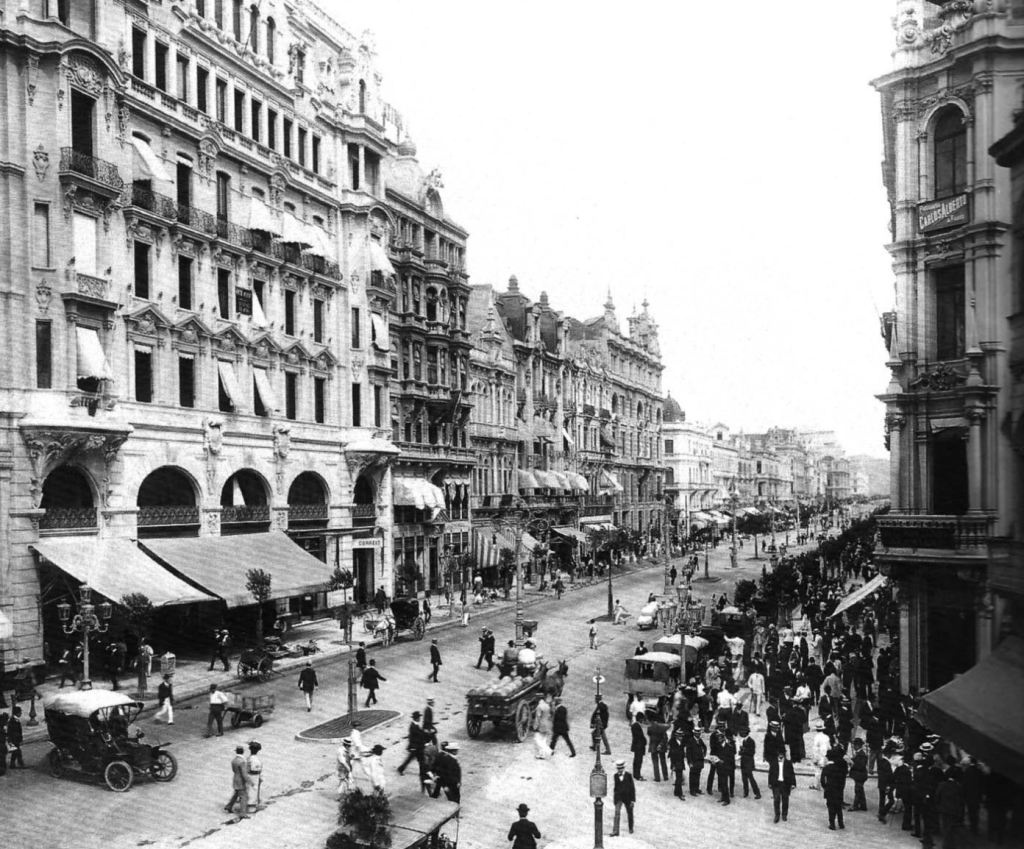 Photographie historique de l’Avenida Central à Rio de Janeiro vers 1910, montrant les bâtiments monumentaux, les piétons, les automobiles et les voitures hippomobiles.
