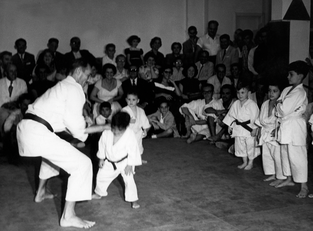Photographie collective de pratiquants de l’Académie Gracie réunis dans leur salle d’entraînement à Rio de Janeiro dans les années 1950.