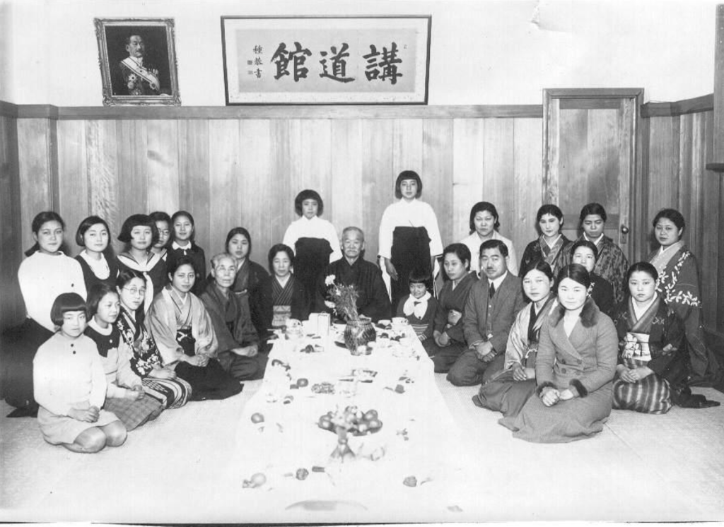 Photographie historique de Jigorō Kanō entouré des membres de la section féminine du Kōdōkan à Tokyo, vers 1935, illustrant l'enseignement du judo aux femmes au Japon.