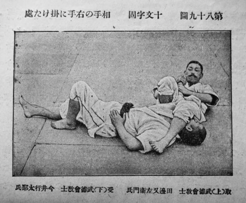 Photographie historique de deux judokas japonais exécutant une technique de contrôle articulaire au sol, extraite du manuel Jūdō Kyōhan de Yokoyama et Ōshima, édition de 1921.
